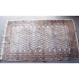 A 20th century rug with repeating motif to central field over a beige ground,