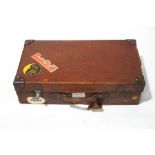 A vintage leather suitcase, with various luggage labels, 62cm wide.