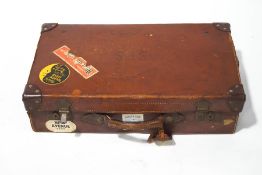 A vintage leather suitcase, with various luggage labels, 62cm wide.