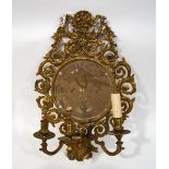 A brass framed wall mirror with round bevelled mirror plate issuing three candle sconces,