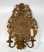 A brass framed wall mirror with round bevelled mirror plate issuing three candle sconces,