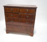 A George III walnut chest of two short and three long drawers, with brass handles and bracket feet,