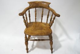 A late 19th century smokers bow shaped chair with solid elm seat and turned legs linked by four
