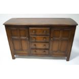 An Ercol dark wood sideboard, four central drawers flanked by cupboard,