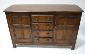 An Ercol dark wood sideboard, four central drawers flanked by cupboard,