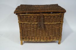 A wicker fishing creel with leather buckle strap fastening, 39cm high x 50xm wide x 38cm deep.