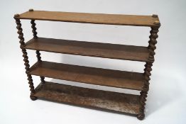 A 19th century oak four tier standing bookshelf with barley twist supports on bun feet,
