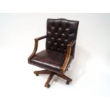 A leather button back office chair on swivel base with four splayed legs and plastic casters.