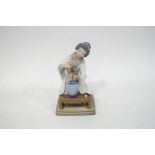 A Lladro figure of a Japanese lady in traditional dress, arranging flowers in a vase,
