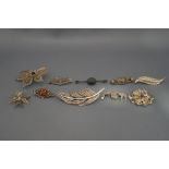 A collection of ten silver and silver coloured brooches,