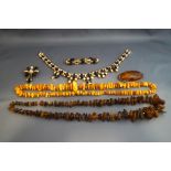 A large oval amber brooch; an amber necklace, 55g gross; another amber necklace,