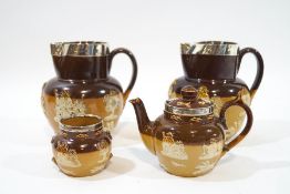 A pair of Royal Doulton saltglazed stoneware jugs, mounted with silver rims, 15cm high,