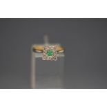 An emerald and diamond ring, stamped '18ct', the square cut stone enclosed by twelve single cuts,