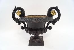 A cast iron two handled garden urn in the Classical style, painted black with gilt detail,