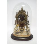 A Victorian brass skeleton clock under a glass dome, on associated base, with pendulum and key,