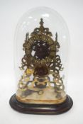 A Victorian brass skeleton clock under a glass dome, on associated base, with pendulum and key,
