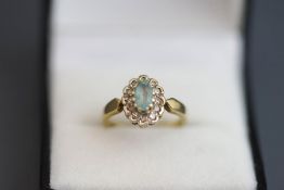 An aquamarine and diamond 9 carat gold cluster ring, the oval cut enclosed by single cuts,