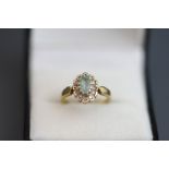 An aquamarine and diamond 9 carat gold cluster ring, the oval cut enclosed by single cuts,