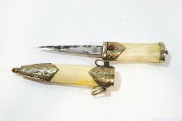A small Indian dagger within a bone scabbard, white metal mounts inset with red hardstone,