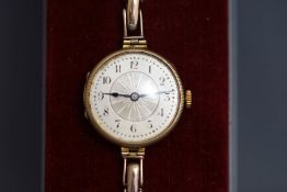 A lady's 9 carat gold wristwatch, with coin milled edge to the hinged case,