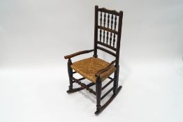 A small Country oak rocking chair with spindle back and rush seat