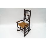 A small Country oak rocking chair with spindle back and rush seat