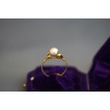 A single stone cultured pearl ring, stamped '14K', the greyish pearl of approximately 7 mm diameter,