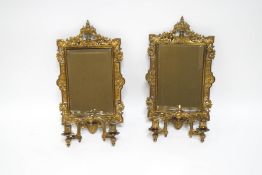 A pair of ornate pierced brass mirrored wall sconces with bevelled glass,