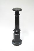 A serpentine marble torchere, the carved fluted column upon an octagonal stepped base,