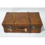 A vintage leather steamer trunk with black interior, including a drop-in tray and clasped pouch,