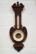 A Victorian mahogany aneroid barometer with carved applied mounts and visible workings,