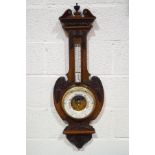 A Victorian mahogany aneroid barometer with carved applied mounts and visible workings,