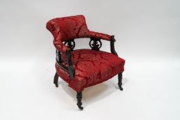 An Edwardian tub armchair with pierced ebonised frame,