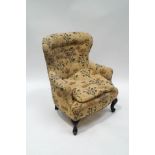A late Victorian button back armchair with plant patterned upholstery, on cabriole legs,