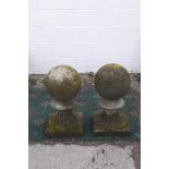 A pair of reconstituted stone weathered gate post spherical finials,