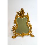 A Victorian strut mirror with bevelled glass, Rococo style scroll frame and cherub mount,