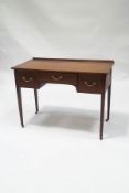 An Edwardian mahogany writing desk with three drawers, upon square tapering legs,