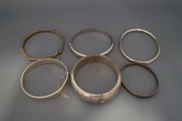 A collection of six silver and silver coloured bangles