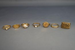 A 9 carat gold ring set with a small Mexican coin; four other 9 carat gold rings; 12.