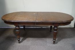 A Victorian mahogany dining table with one loose leaf on turned and reeded legs, with brass casters,