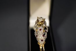 A diamond and ruby panthers bangle, stamped '9K',