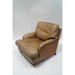A leather armchair with turned and reeded legs on brass casters,