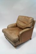 A leather armchair with turned and reeded legs on brass casters,
