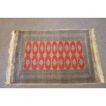 A Middle Eastern rug with central repeating diamond motif to a red ground,