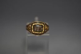 A George IV mourning ring, the glazed hair panel enclosed by chasing and black enamel,