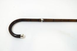 A slim bamboo walking stick with horn handle and silver tip and band, London hallmark,
