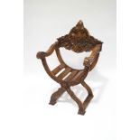 A 19th century Venetian walnut X-frame chair, with slatted seat below a heavily carved back,