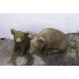 Two reconstituted stone garden pig ornaments,