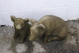 Two reconstituted stone garden pig ornaments,