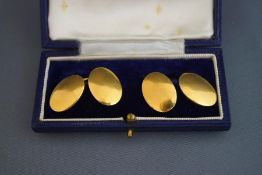 A pair of cufflinks, the plain oval panels stamped '18ct', 17.